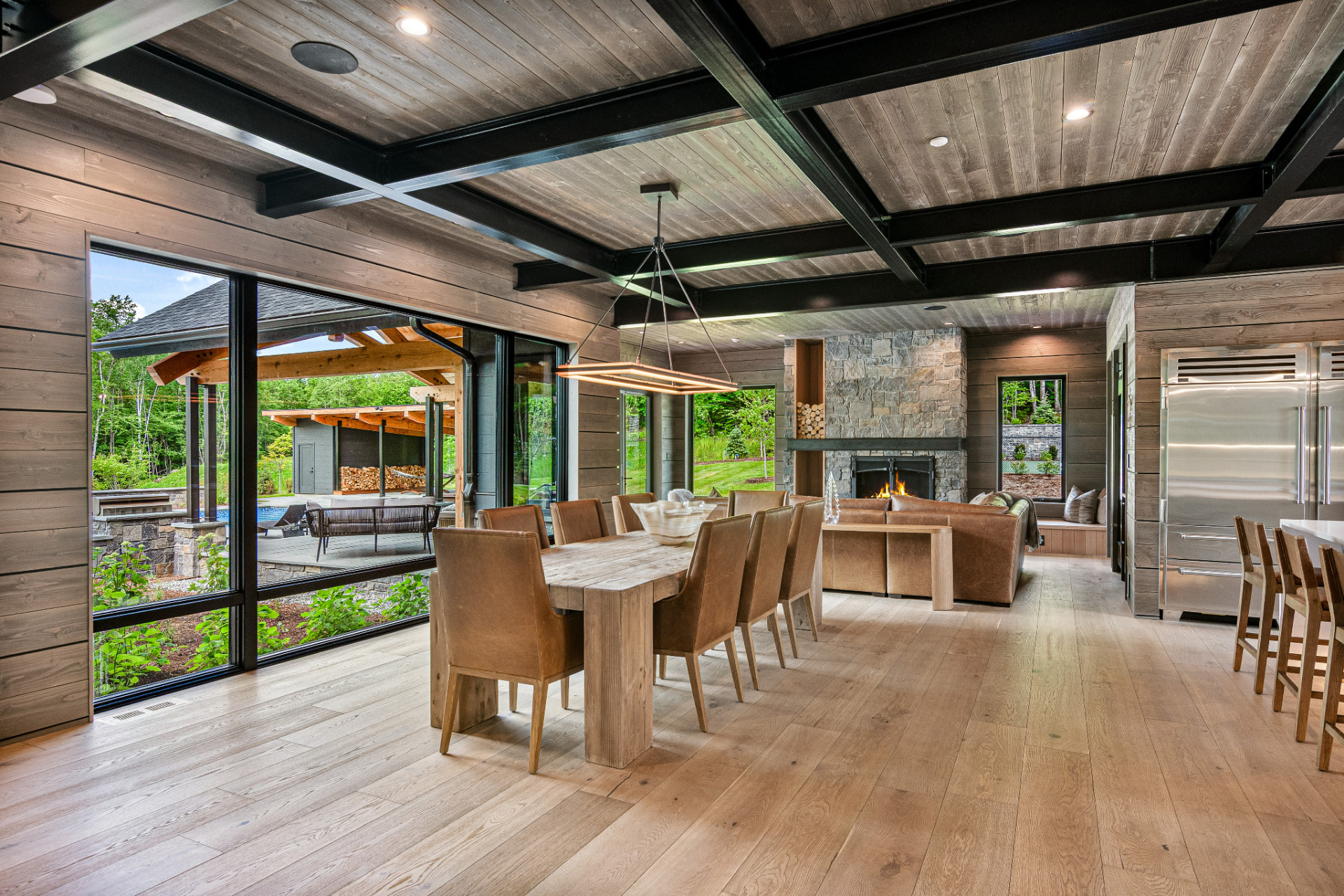 Open dining area with beamed ceiling, stone fireplace, and wood walls