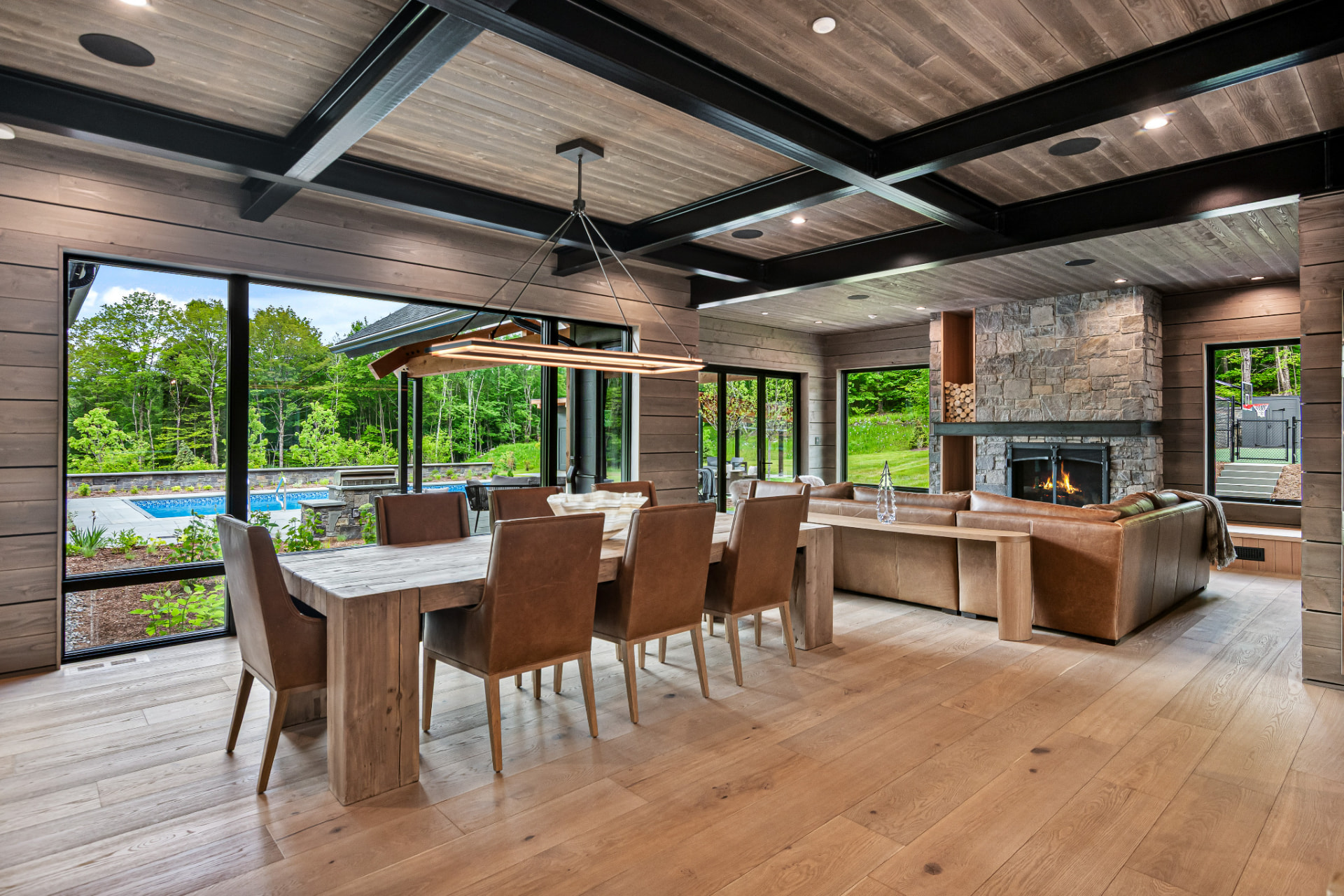 Dining and living space with black beam ceiling detail and stone fireplace